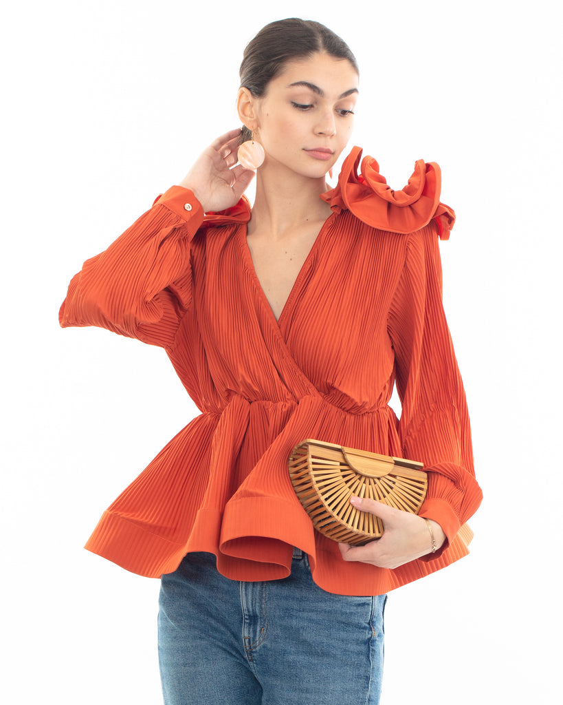 Pleated shirt with ruffle hem and floral design on shoulder in orange
